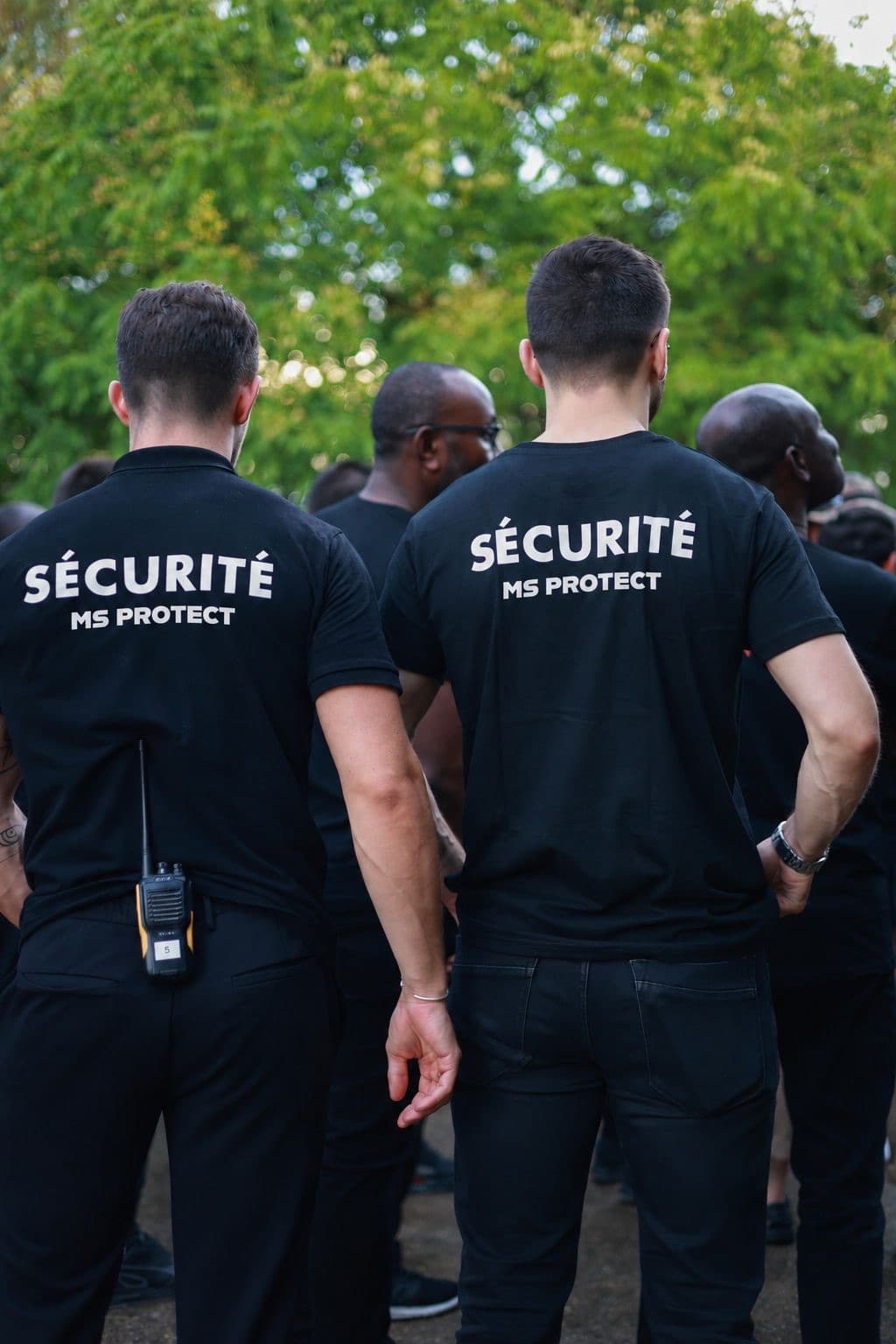 Équipe d'agents MS Protect de dos, talkie-walkie à la ceinture